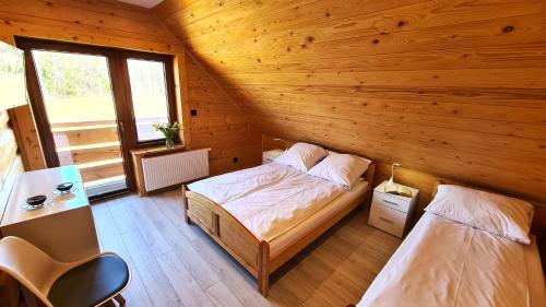 2 letti in una camera con pareti in legno di Drewniana chata 