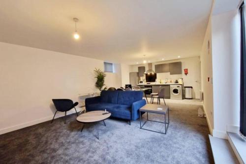 ein Wohnzimmer mit einem blauen Sofa und einem Tisch in der Unterkunft FREE PARKING - Stunning 2-BR near Salford Royal in Manchester