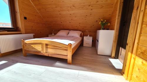 a wooden room with a bed and a refrigerator at Drewniana chata in Cisówek