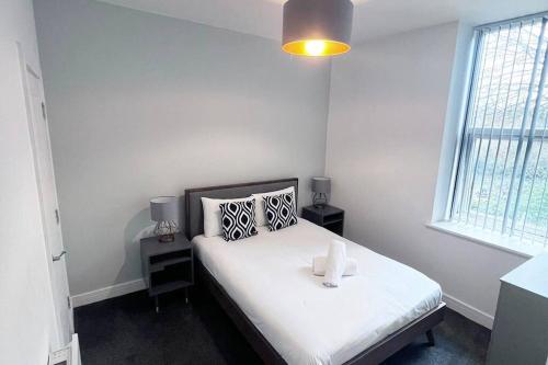 a bedroom with a bed with white sheets and a window at FREE PARKING - Stunning 2-BR near Salford Royal in Manchester