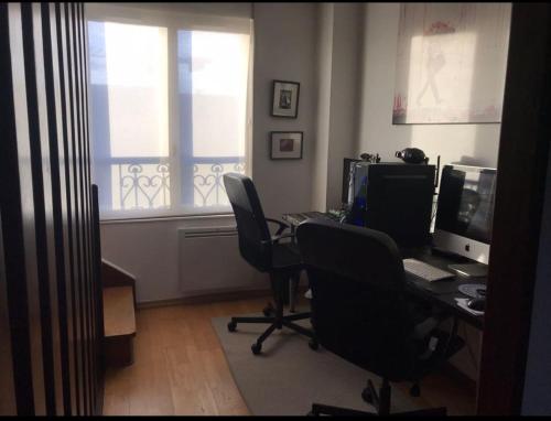 ein Büro mit einem Schreibtisch mit zwei Computern und einem Fenster in der Unterkunft Le Rosiers in Poissy