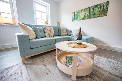 salon z niebieską kanapą i stołem w obiekcie Voll ausgestattetes, neues Rennsteig Apartment Ruhla w mieście Ruhla