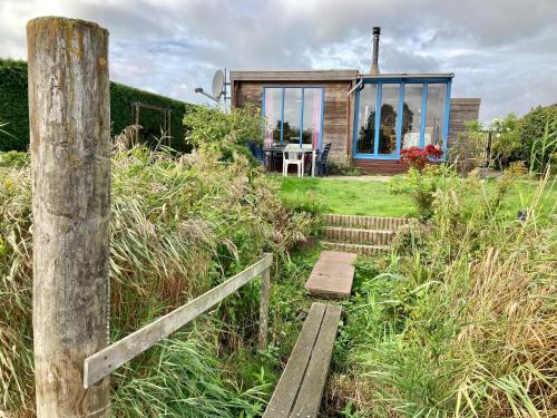 a small house with glass windows on a field at 4pers - House w Sauna, Winter garden fishing pier in front of the Lauwersmeer in Anjum