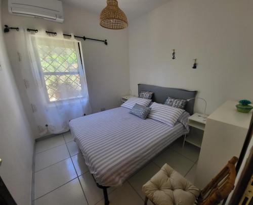 Una cama doble en una habitación con ventana. en Villa Chiccolina, en Stintino