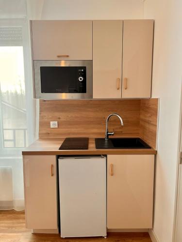 une cuisine avec un évier et un micro-ondes dans l'établissement Studio 4 pers face gare SNCF Appart Hotel le Cygne D4, à Bourges