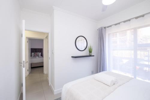 a white bedroom with a bed and a window at Ballito Village Luxury Apartments in Ballito