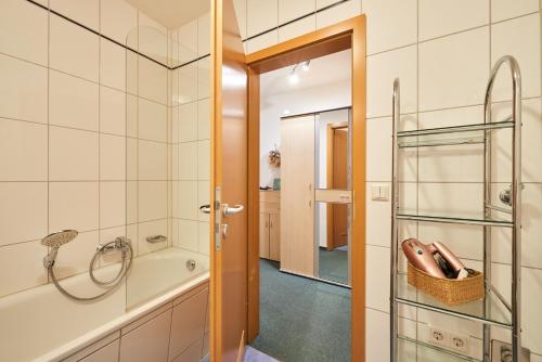 un bagno con vasca, doccia e porta in vetro di FeWo "Strandburg-Küken" 9005 - Fehmarn a Fehmarn