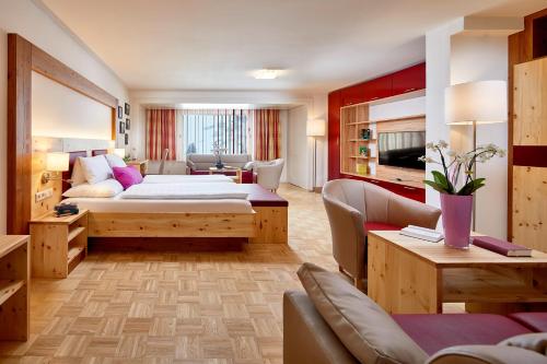 オーバータウエルンにあるホテル アルピナのベッドとリビングルームが備わるホテルルームです。
