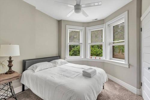 ein weißes Schlafzimmer mit einem Bett und zwei Fenstern in der Unterkunft Side by Side Townhomes in Tower Grove 916&918 in Tower Grove
