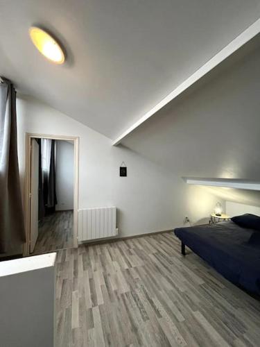 a white room with a bed and a wooden floor at La perle bleue 45m² 4 personnes in Orchies