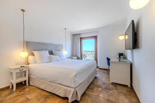 a bedroom with a large white bed and a window at La Posada del Mar in Denia