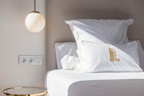 a bedroom with a bed with white pillows and a table at La Posada del Mar in Denia