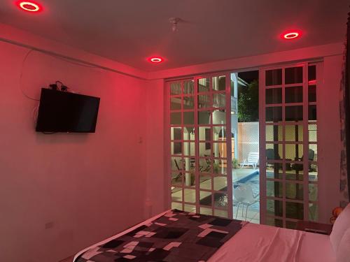 a room with a bed and a tv on a wall at HCEAS villa is 5 min fr. airport & to the beaches in Bon Accord