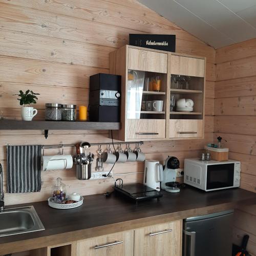 a kitchen with wooden walls and a counter with a microwave at Purvēveri in Tukums