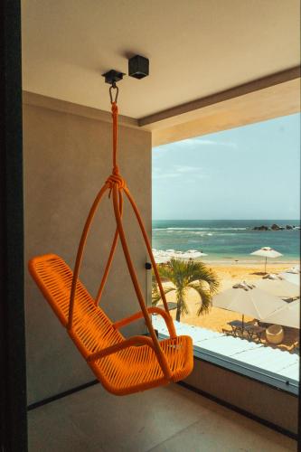 an orange swinging chair in front of a beach at Marilyn Pousada Morro in Morro de São Paulo