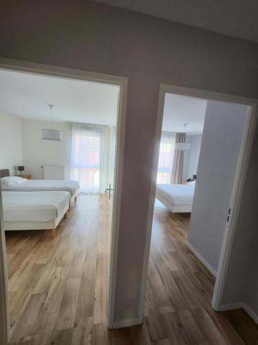 een kamer met 2 bedden en een slaapkamer met een spiegel bij DOMITYS - Le Fil de Soie in Calais