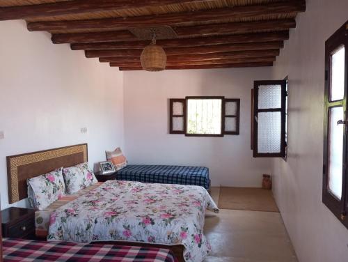 a bedroom with a bed and a couch and windows at Dar Lala Zhour in Aïn Bouchrik
