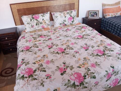 a bedroom with a bed with pink flowers on it at Dar Lala Zhour in Aïn Bouchrik
