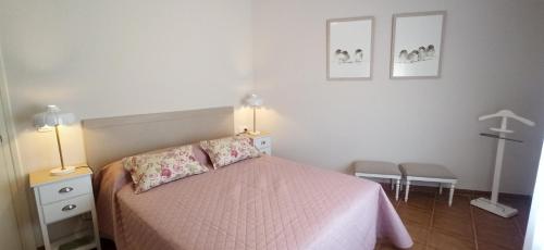 a bedroom with a bed with pink sheets and two lamps at Ca La Silvia Masboquera in Mas Boquera