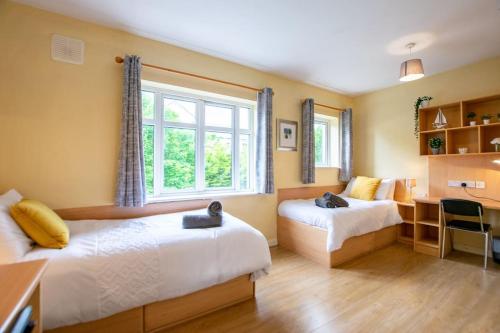 1 dormitorio con 2 camas, escritorio y ventana en 122 - Large Duplex with Parking by Shortstays en Galway
