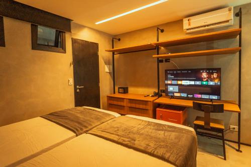 een slaapkamer met een bed en een bureau met een televisie bij Marilyn Pousada Morro in Morro de São Paulo