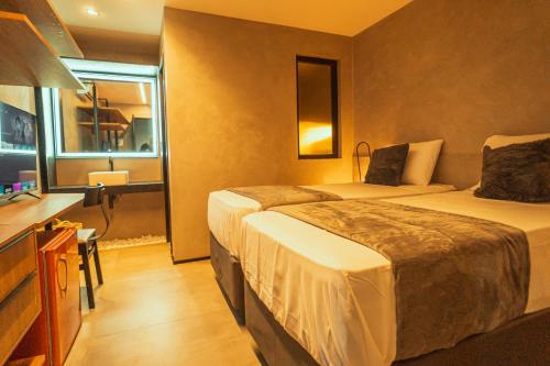 a hotel room with two beds and a desk at Marilyn Pousada Morro in Morro de São Paulo