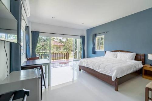 Schlafzimmer mit blauen Wänden, einem Bett und einem Schreibtisch in der Unterkunft Lay Back Villa C1with kitchen & High Speed Internet in Krabi