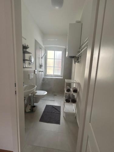 a white bathroom with a sink and a toilet at CityLake G23 Apartments mit kostenloser Parkmöglichkeit !! in Gmunden