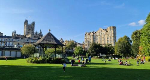 a group of people in a park with buildings in the background at Charming Apartment in the Heart of Bath in Bath