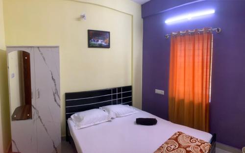 Cozy Prime-3BHK Near BIEC Exhibition Bangalore & IKEA في بانغالور: غرفة نوم بسرير وستارة برتقال