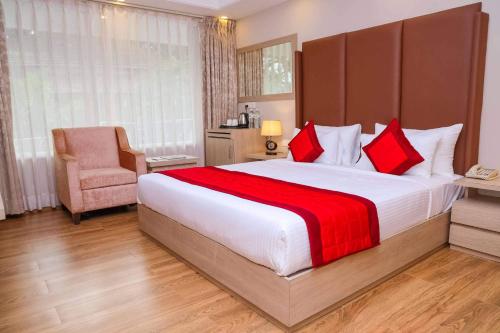1 dormitorio con 1 cama grande con almohadas rojas y silla en Hotel Heera Executive, en Nandurbār