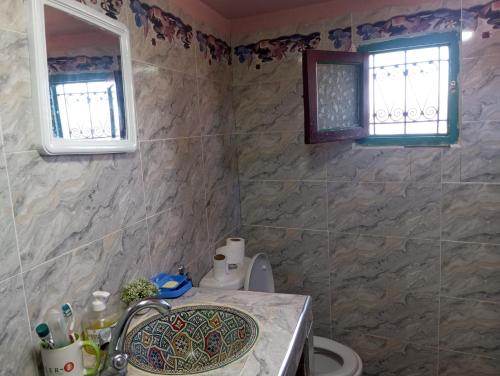 a bathroom with a sink and a toilet and two windows at Dar Lala Zhour in Aïn Bouchrik