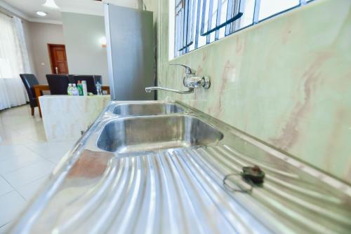un lavandino in acciaio inossidabile con rubinetto su un muro di GOWON BnB a Bunju