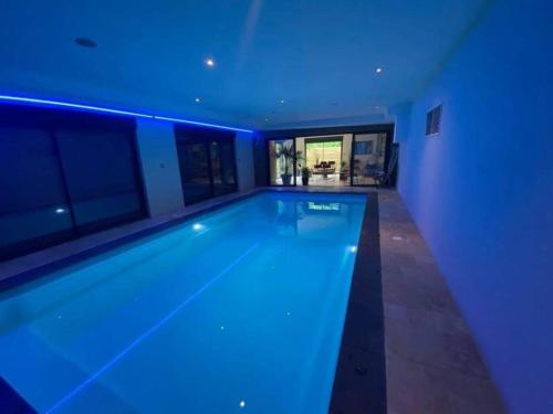 - une piscine avec des lumières bleues dans une maison dans l'établissement Nuit insolite à la campagne, à Fiennes
