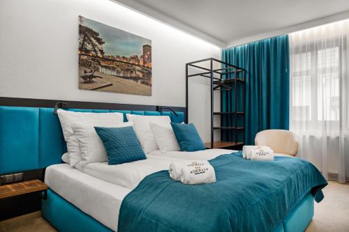 a blue and white bedroom with a bed with towels on it at Pensjonat eSENtia in Zgorzelec