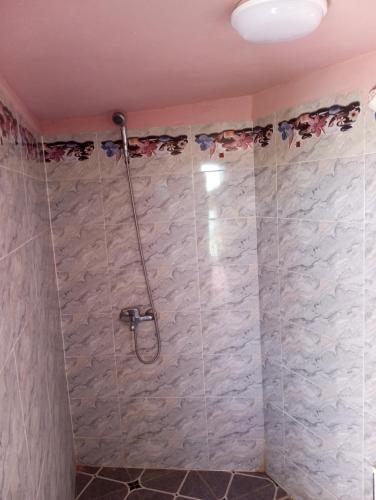 a shower in a bathroom with a tiled wall at Dar Lala Zhour in Aïn Bouchrik