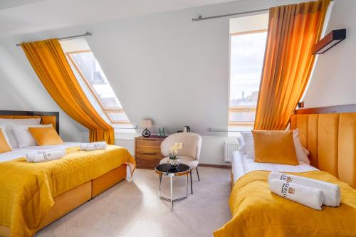 two beds in a room with yellow sheets and a table at Pensjonat eSENtia in Zgorzelec