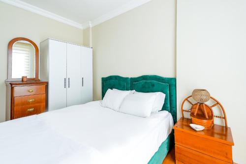 een slaapkamer met een wit bed en een houten dressoir bij Cozy Flat with Balcony 10 min to Hadrian Gates in Antalya