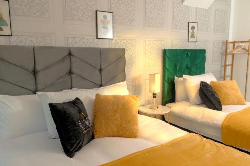 a hotel room with two beds with yellow and black pillows at A Cosy, Elegant 3 Bed Suite in Killingbeck