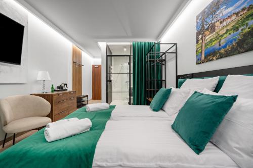 a bedroom with two white beds with green pillows at Pensjonat eSENtia in Zgorzelec