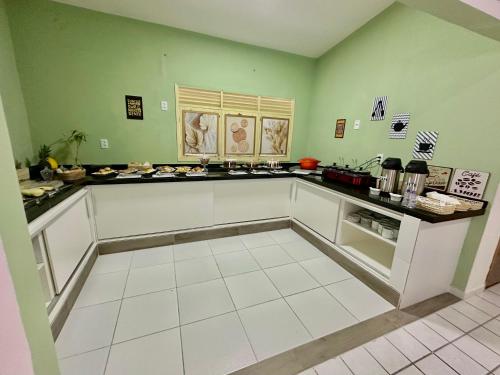 a large kitchen with green walls and white counters at Pousada Manaíra in João Pessoa