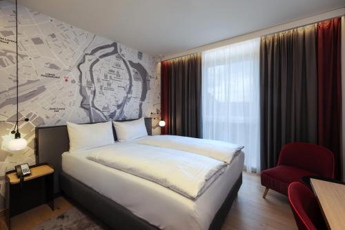 a hotel room with a bed and a red chair at IntercityHotel Lübeck in Lübeck