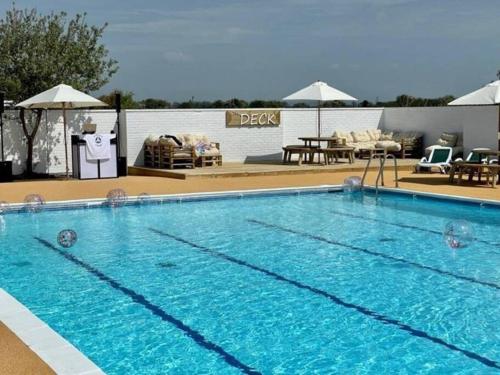 a large blue swimming pool with tables and chairs at 25. Valencia in Selsey