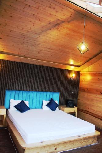 a bed in a room with a wooden ceiling at THE GRAND RESORT DHANOLTI in Dhanaulti