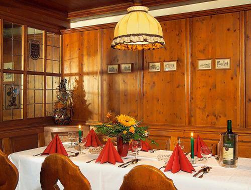 ein Esszimmer mit einem Tisch mit Blumen und einem Kronleuchter in der Unterkunft Altdeutsches Gasthaus Roter Hirsch in Jena