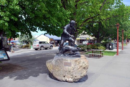 a statue of a man with a dog on a rock at Pinewood Motels in Fairlie