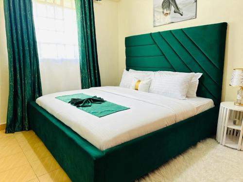 een bed met een groen hoofdeinde in een kamer bij The Cosy Corner in Kisii