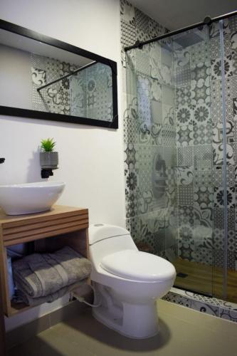 a bathroom with a toilet and a sink and a shower at Hotel Boutique Ciudad Jardin in Cali