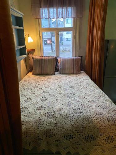 a bedroom with a bed with two pillows and a window at Nummenpakan Pysäkki in Turku