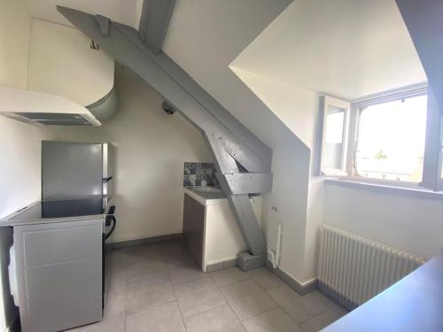 eine Küche mit einer Treppe, einem Kühlschrank und einem Fenster in der Unterkunft apt cozy refait à neuf à 5min du centre ville in Saint-Hilaire-du-Harcouët